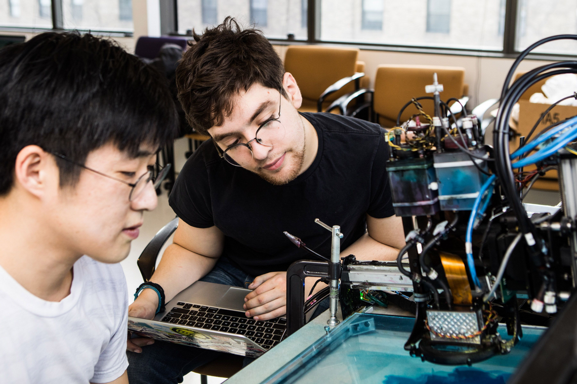 Студент электротехнического факультета MIT с преподавателем работают над новым устройством 